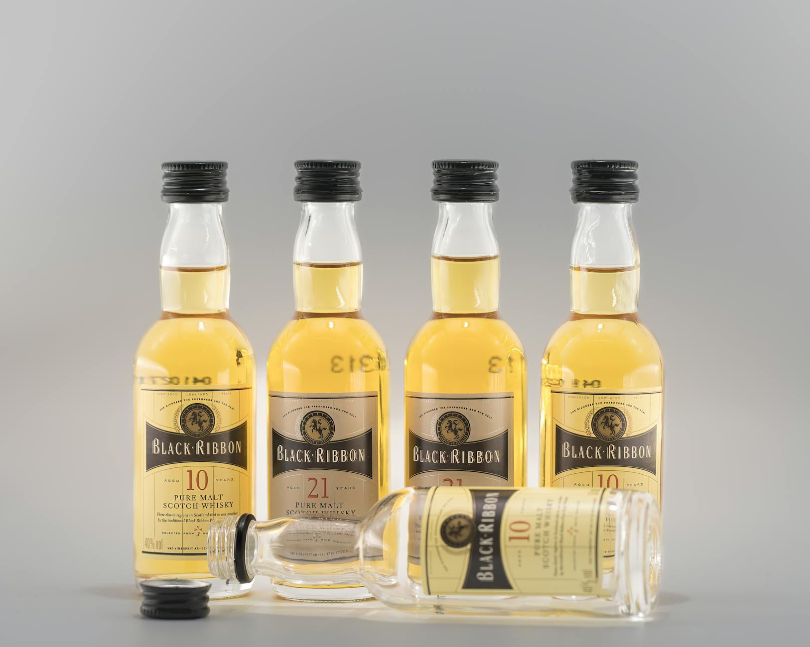 Prezent dla miłośnika whisky: co kupić zamiast kolejnej butelki Pięć butelek whisky Black Ribbon na szarym tle
