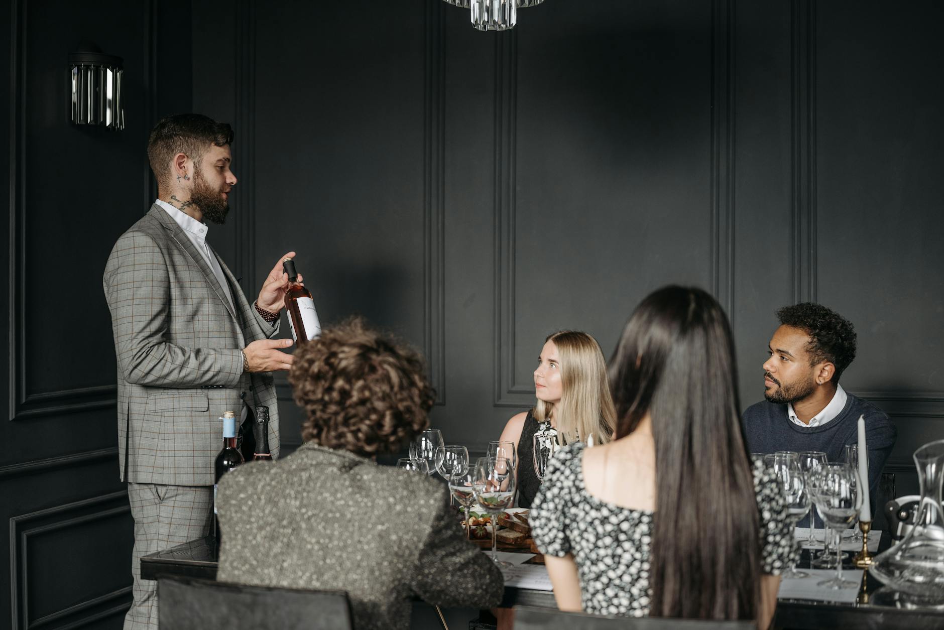 Sommelier prezentuje wino dorosłym uczestnikom degustacji w eleganckiej sali